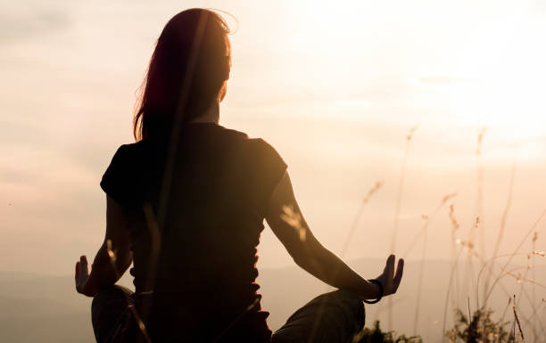 Silhouette of young woman practicing yoga outdoors